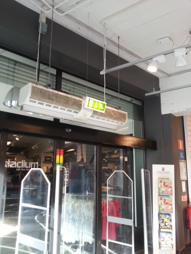 Luftridå med smutsigt insugsgaller ovan en entre till en butik